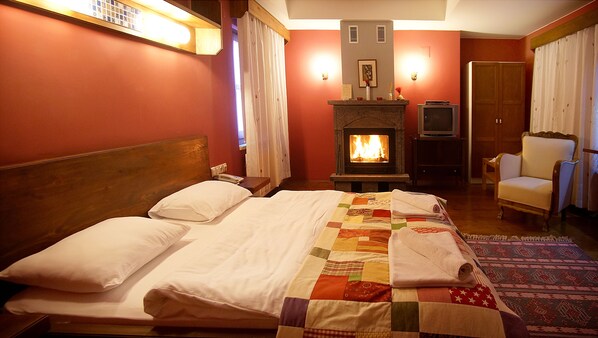 A hotel room with a bed, a fireplace, a television, and a chair. - Kisik Konagi (Ayvacik)