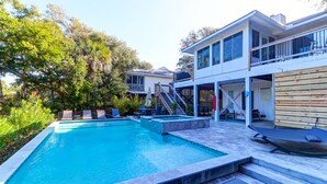 Et moderne hus med swimmingpool, udendørs siddepladser og en overdækket terrasse.