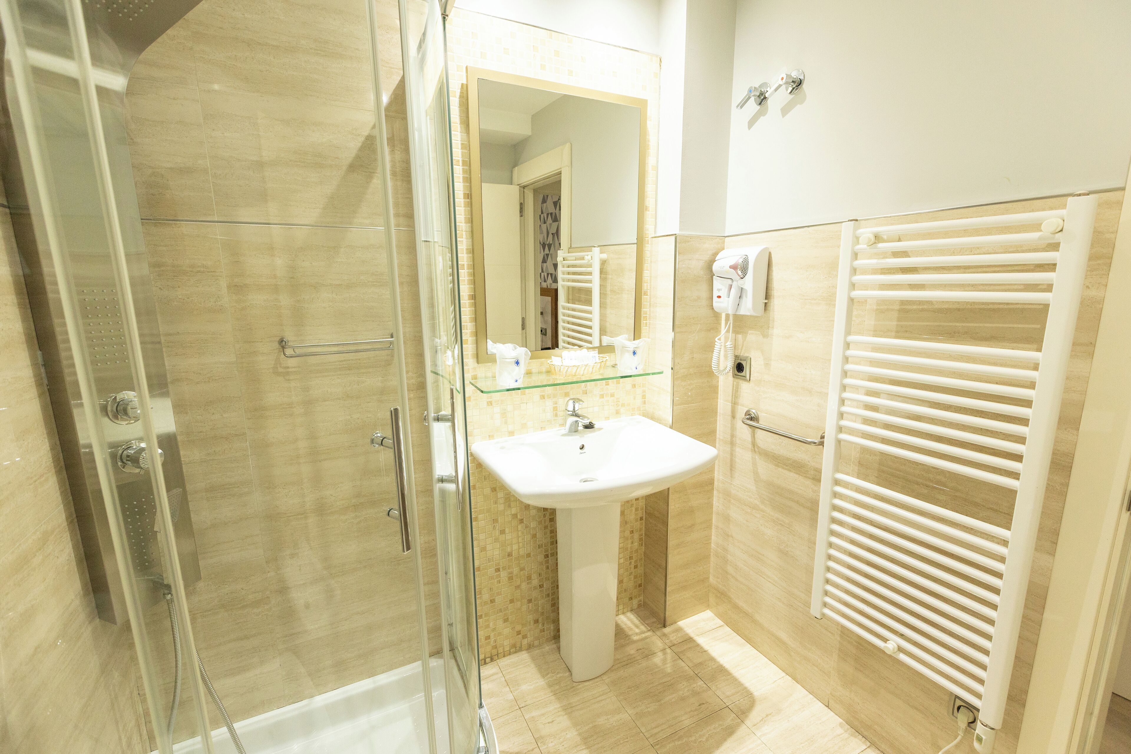 Un bagno moderno con cabina doccia in vetro, un lavandino bianco e un porta asciugamani.