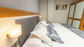 A neatly made bed with a headboard, a bedside lamp, and a wall-mounted light.