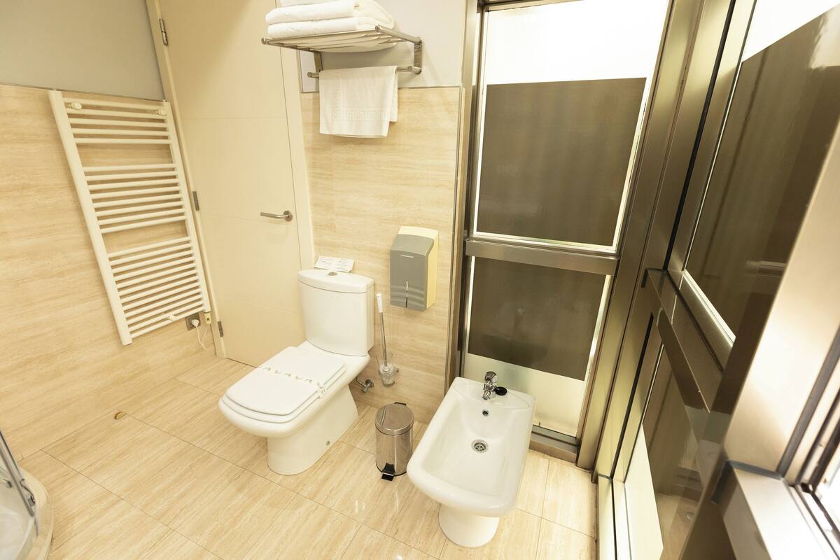 A modern bathroom with a toilet, bidet, and shower area.