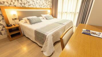 Une chambre d’hôtel avec un lit, une table de chevet et une petite table en bois.