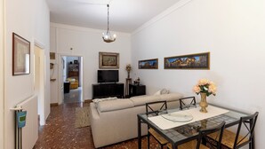 A living room with a sofa, a dining table with chairs, a TV, and framed pictures on the wall. - Get the local feel in a nice and safe neighborhood in the heart of Rome! (rome)