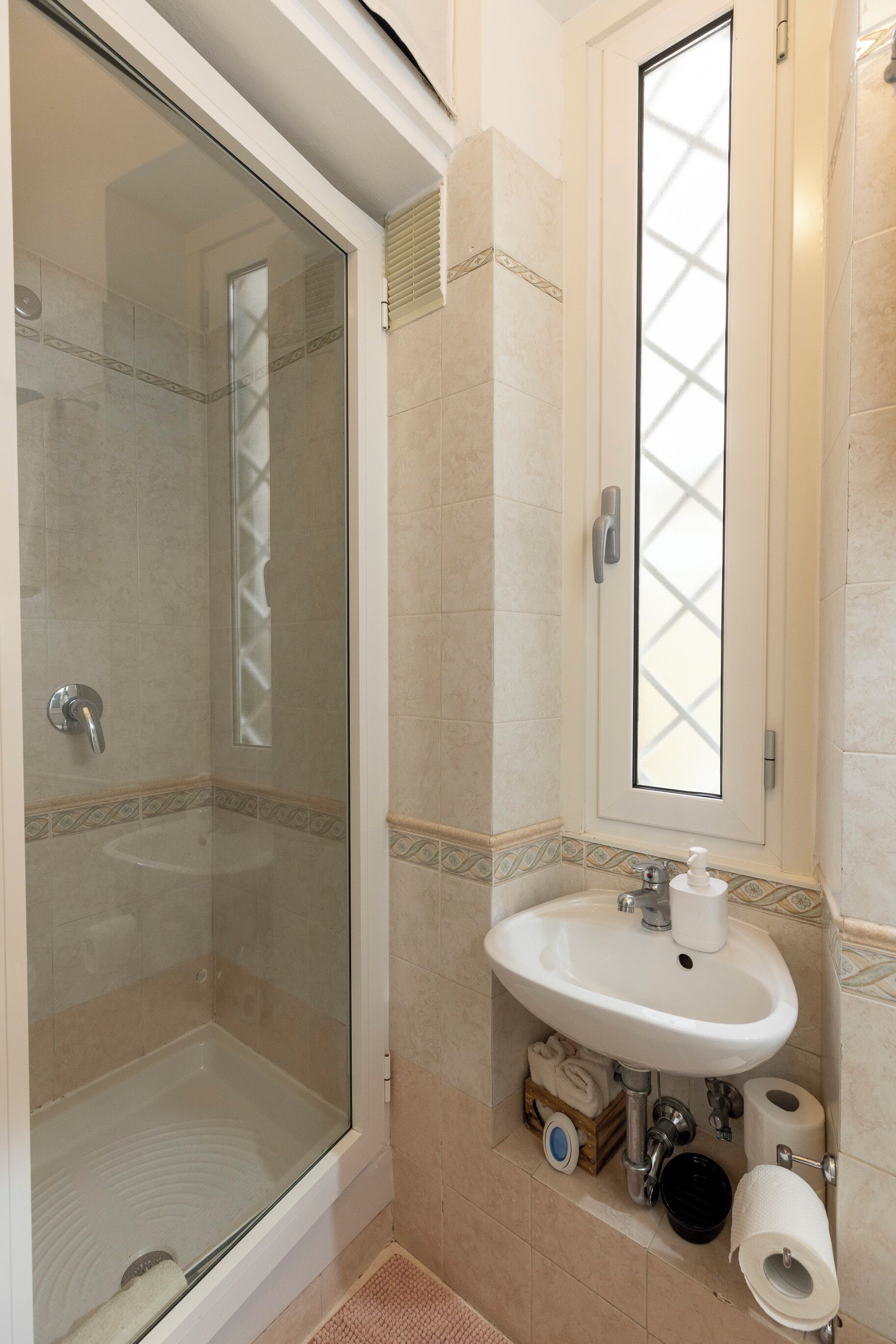 A bathroom with a glass-enclosed shower, a sink with a mirror, and a toilet.