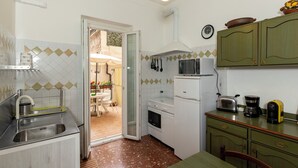 A compact kitchen with a sink, stove, microwave, and a dining area with a table and chairs. - Get the local feel in a nice and safe neighborhood in the heart of Rome! (rome)