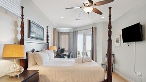 Habitación de hotel con cama con dosel, ventilador de techo, televisión de pantalla plana y vistas al exterior.