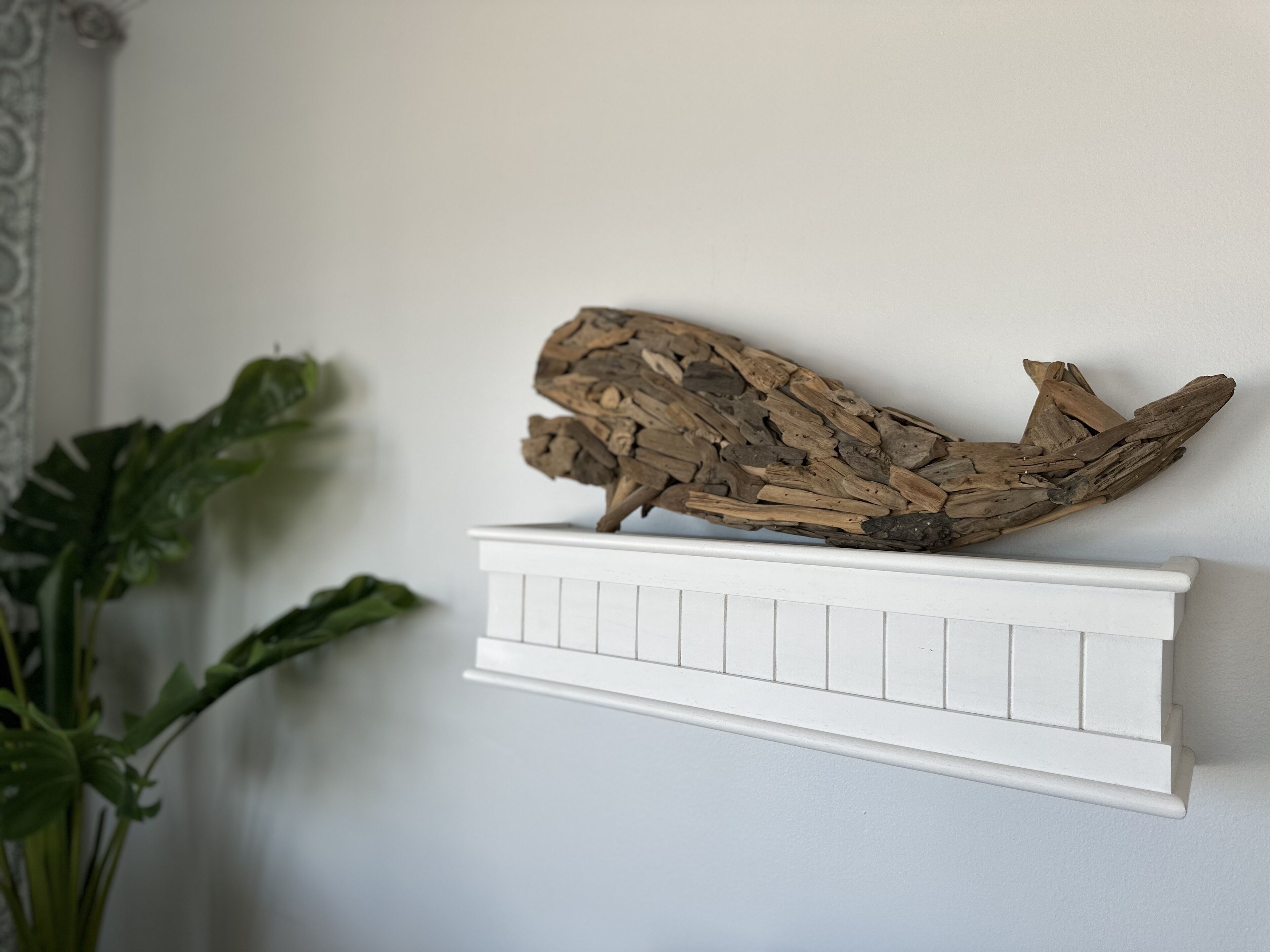 A white shelf with a piece of driftwood.