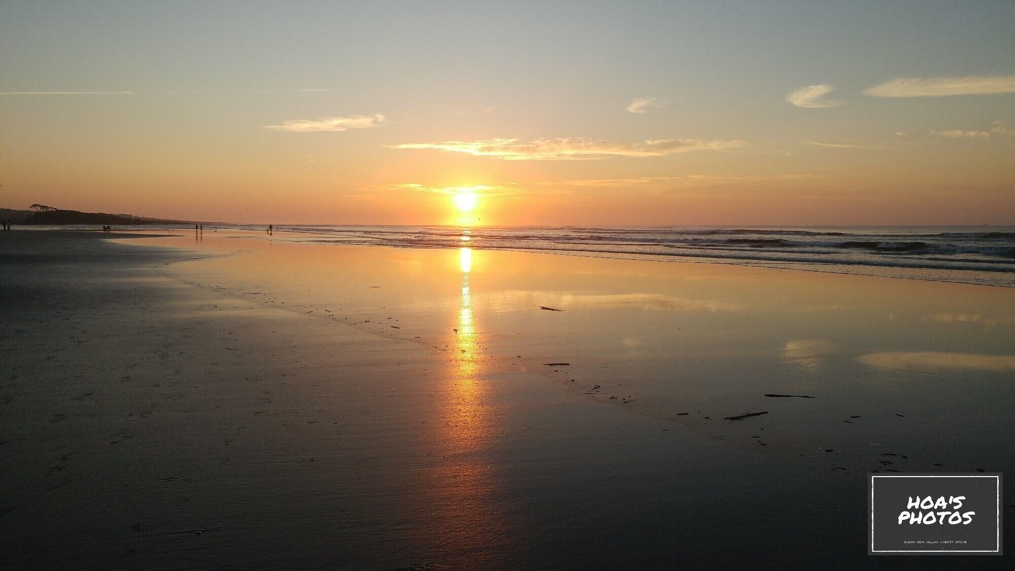 Une plage au coucher du soleil, avec un ciel dégagé et une mer calme.