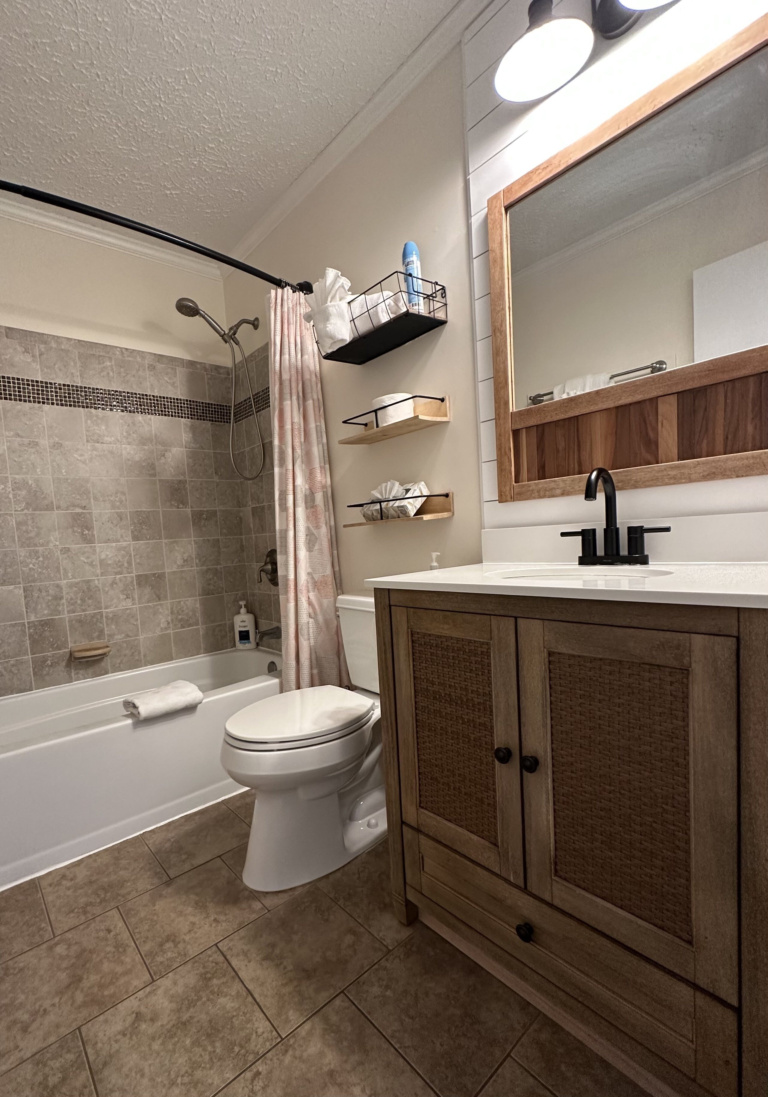 A bathroom with a shower, toilet, and vanity with a mirror.