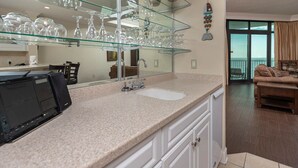 Une cuisine moderne avec une vitrine où sont exposés des verres à vin, un grand miroir et une vue sur le balcon.