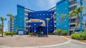 Ein blaues Hotel mit Innenhof, Palmen und blauem Himmel.