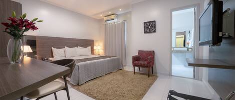 Une chambre d’hôtel moderne équipée d’un lit, d’une table de chevet, d’une lampe, d’une chaise et d’un coin repas avec une table et des chaises.