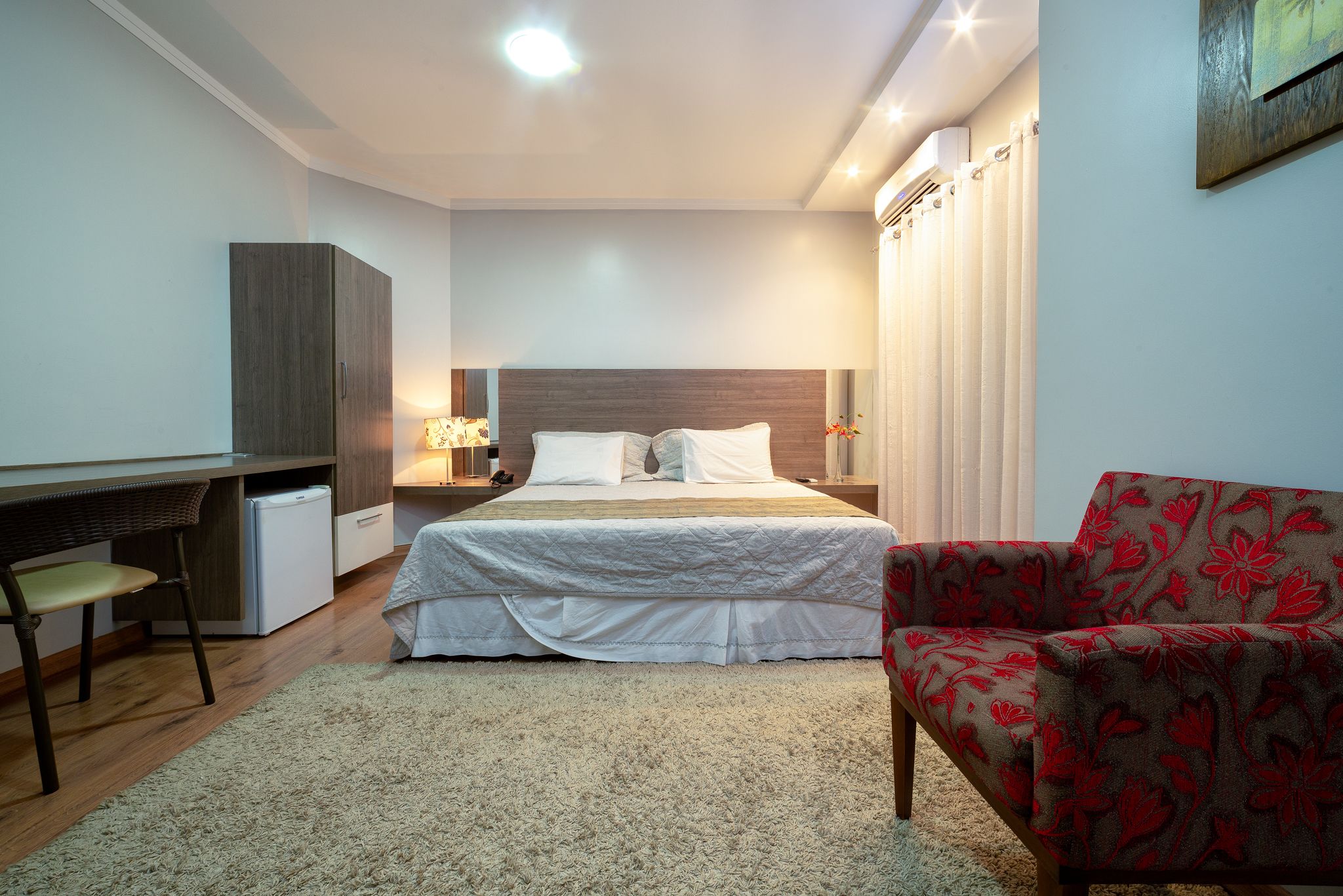 A bedroom with a bed, a desk, a chair, and a wardrobe.