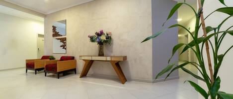 A reception area with a modern console table, two wicker sofas, and a large mirror.