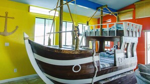 Una habitación con una cama litera, una decoración de barco de madera y una ventana con persianas.