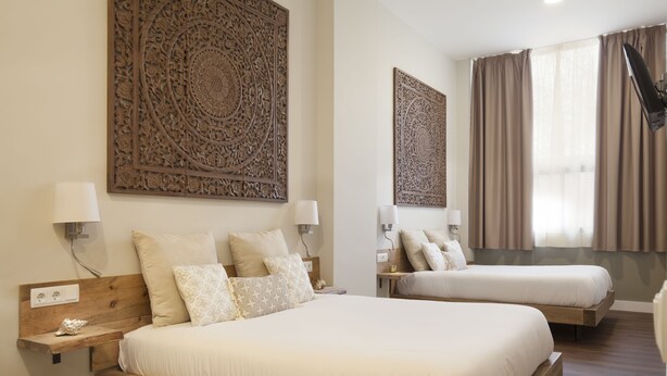 Une chambre d’hôtel avec deux lits, un grand élément décoratif mural et une fenêtre avec des rideaux.