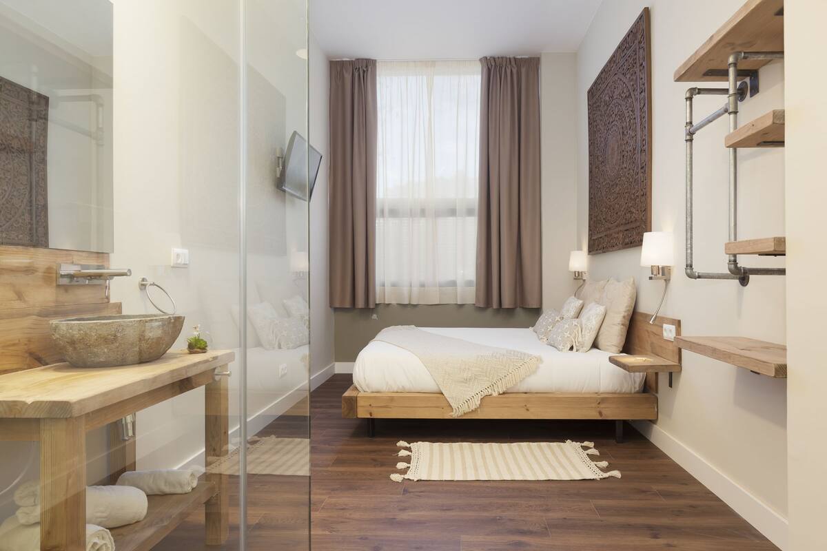Un dormitorio moderno con una cama de madera, un cerramiento de ducha de vidrio y un espejo grande.