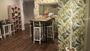 Un coin repas avec une table et des chaises en bois, entouré d’étagères et d’un mur orné d’un motif végétal.