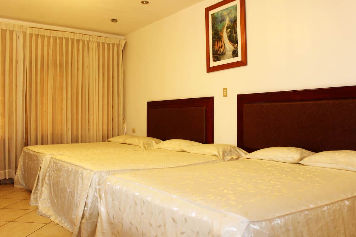 Une chambre d’hôtel avec deux lits simples, une grande fenêtre avec des rideaux et un tableau au mur.