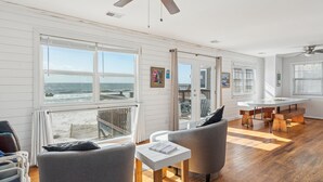 Um quarto amplo com vista para o oceano, um ventilador de teto e uma área de jantar com mesa redonda.