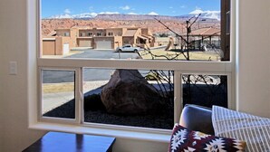 A room with a large window overlooking a parking area and a building with a mountain view. - 10A1 Close to Pool, Views, Huge Patio, Sleeps 8 (Moab)