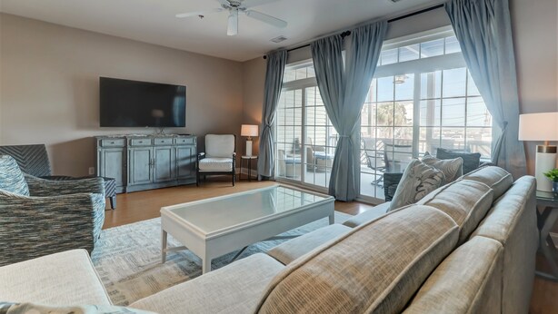 A living room with a sofa, a coffee table, a TV, and a window with curtains.
