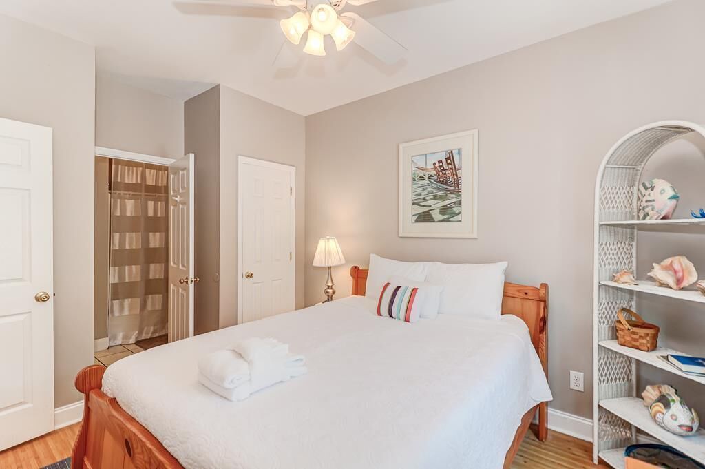 A neatly made bed with white linens and a pillow, a bedside lamp, and a wall-mounted artwork.