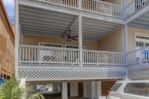 Um edifício com várias andares, varandas, um deck de madeira e um carro estacionado na entrada.