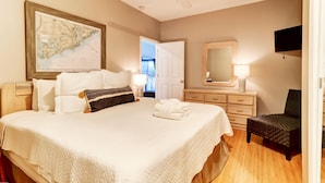A hotel room with a large bed, a ceiling fan, a map on the wall, a TV, and a chair.