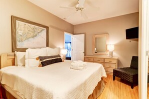 Une chambre d’hôtel avec un grand lit, un ventilateur de plafond, une carte accrochée au mur, une télévision et une chaise.