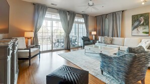 A spacious living room with a sofa, armchairs, a coffee table, and a TV.