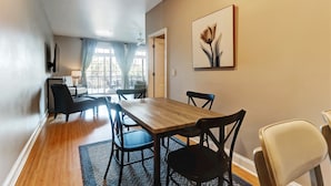 A dining area with a wooden table, black chairs, and a blue rug.