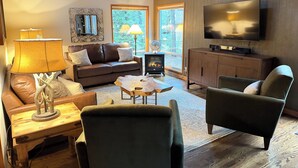 A cozy living room with a leather sofa, a wooden coffee table, a TV, and a fireplace. - Basecamp for endless adventure, perfect Black Butte location - Hot Tub! (Sisters)