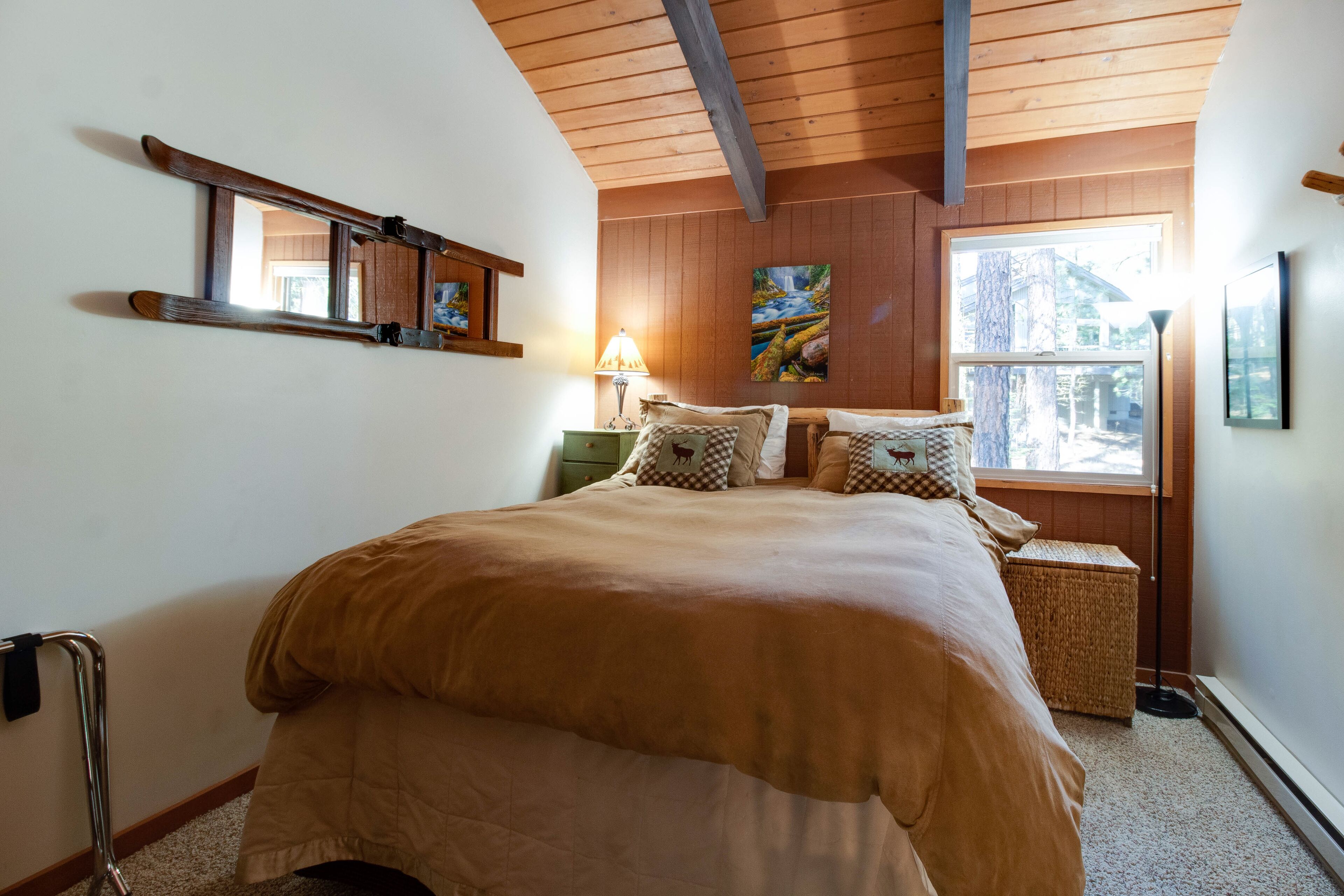 Een slaapkamer met een groot bed, houten balken in het plafond, een raam met uitzicht en een schilderij aan de muur.