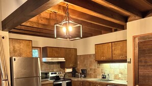 A modern kitchen with a large island, bar stools, and wooden cabinets. - Basecamp for endless adventure, perfect Black Butte location - Hot Tub! (Sisters)