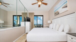 A hotel room with a large bed, a television, a ceiling fan, and a balcony with a view.