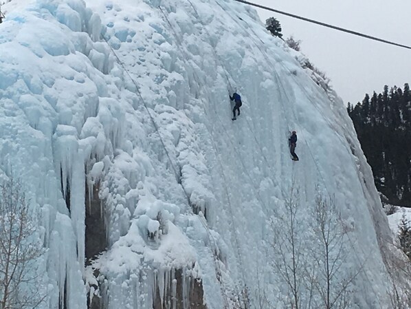 Una gran formación de hielo con dos personas escalándola.