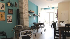 A dining area with multiple tables and chairs, a brick accent wall, and various wall decorations including framed pictures and a bicycle. - Falling Lakes Hostel (Plitvicka Jezera)