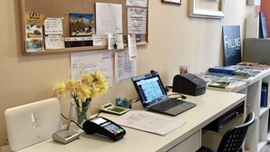 A reception desk with a laptop, a payment terminal, and a vase of flowers. - Falling Lakes Hostel (Plitvicka Jezera)