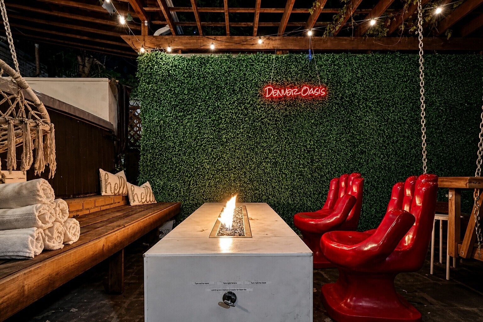 A room with a green wall, a neon sign, a fire feature, and red chairs.