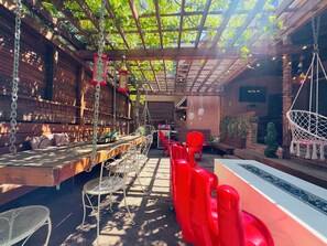 Un espace extérieur abrité, aménagé avec des tables, des chaises et des lanternes suspendues.