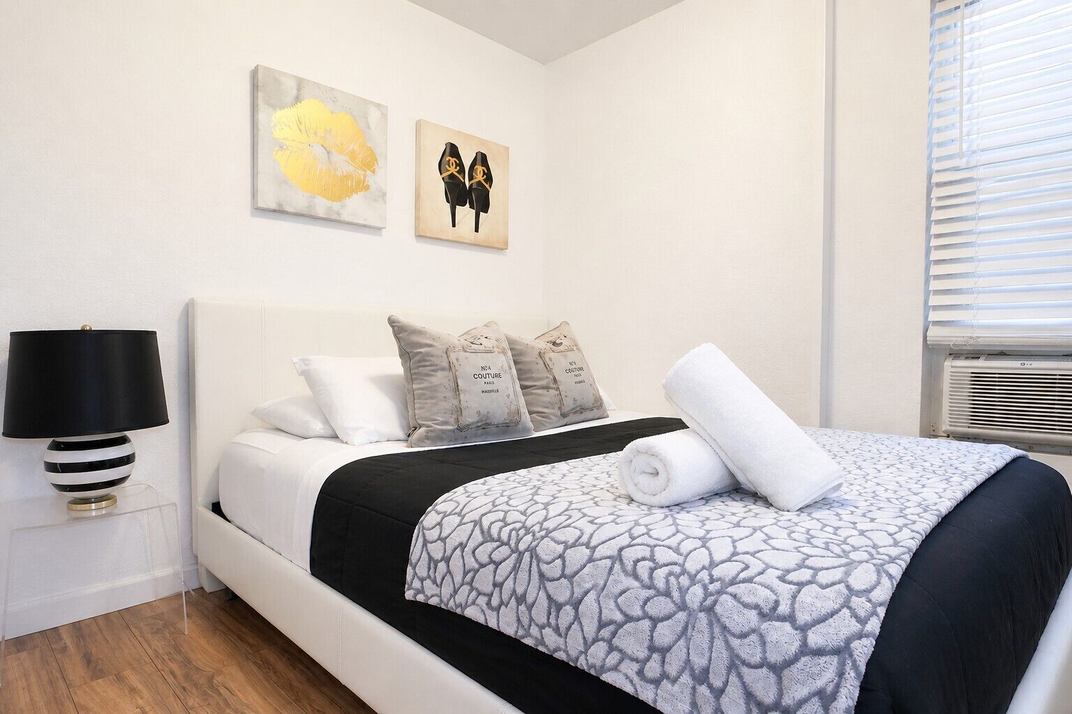 Ein Hotelzimmer mit einem Bett, einer Nachttischlampe und zwei Wandbildern.