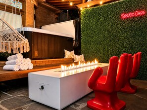 Een wellnessruimte met een verwarmde vloer, een massagetafel, een wandheater en een neonbord waarop 'Denver Oasis' staat.