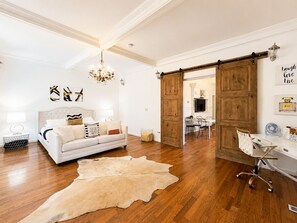 A room with a white sofa, a chandelier, a wooden floor, and a sliding barn door. - Unique , contemporary with HOT TUB!!! (Denver)