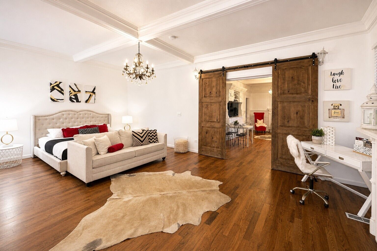A room with a bed, a sofa, a desk, and a chandelier.