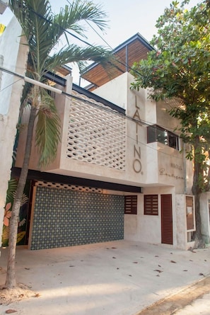 A modern building with a garage door, a textured facade, and the name 'LAINO' on the side.
