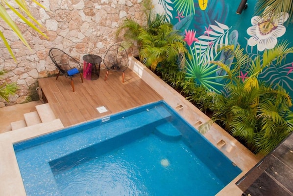 A swimming pool with a stone wall and a mural.