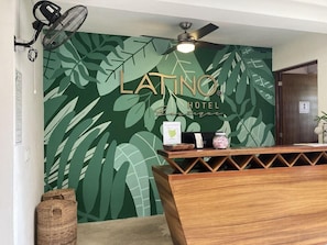 A reception desk with a wooden finish and a green leaf-patterned wall behind it.