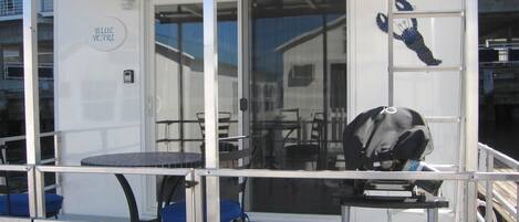 A deck area with a table and chairs, a grill, and a sign that reads "BLUE PEARL".