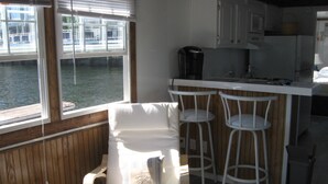 A kitchen with a bar area, wooden paneling, and a view of a dock. -  Houseboat in Boston Harbor Wifi A/C /Heat  Be rocked to sleep (boston)
